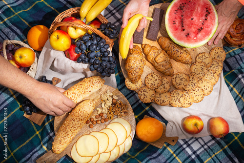 Top view of food laid out and the hands of people during a picnic, flat lay. The concept of summer outdoor recreation on the weekend