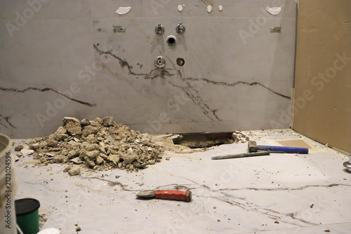 Obraz na plátne Bathroom renovation in progress with broken concrete, construction debris and exposed plumbing beneath a vanity cabinet