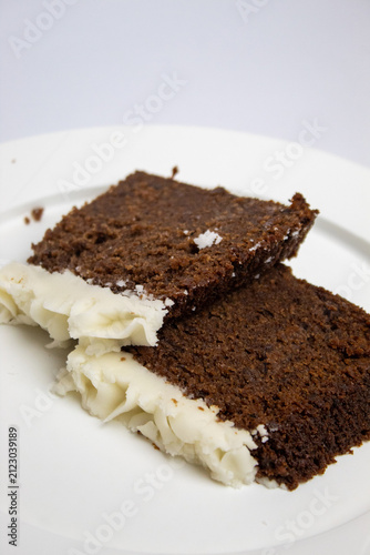 Close-up of two slices of plum cake on a large plate against a white background.