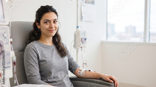 Dialysis patient in chair at clinic smiling near window, medical treatment and care