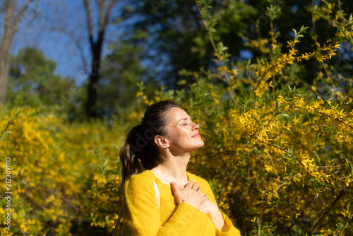 Konstfotografi Tilting her head toward the warm sun, a woman in a yellow sweater embodies spring joy