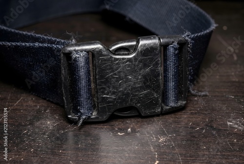 Close up of a plastic buckle on a nylon luggage strap covered in micro-scratches and scuffs