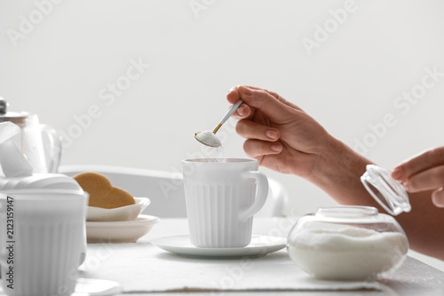 Hand adding sugar to a whit...