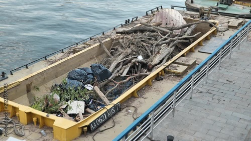 Barge on river carrying collected trash and debris, pollution problem solution