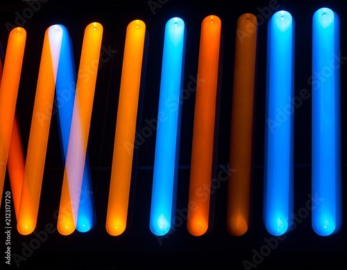 Row of light slits showing different color temperatures from warm orange to cool blue on dark background