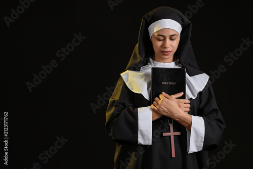 Konstfotografi Young nun with Bible on black background
