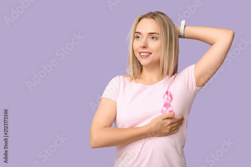 Young woman with pink ribbon on lilac background.  Breast cancer awareness co...