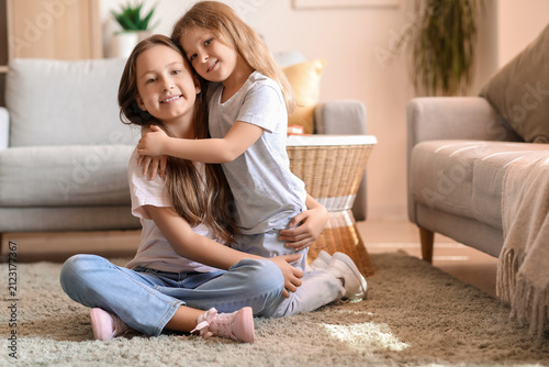 Cute little sisters hugging at home