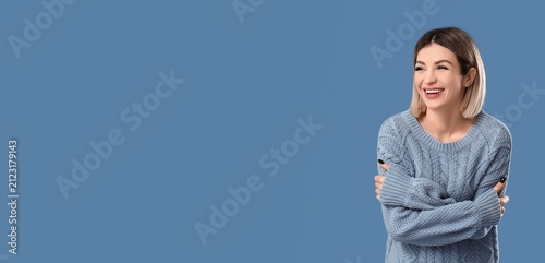 Cuadro en lienzo Smiling young woman in a blue knitted sweater with arms crossed, looking away wi