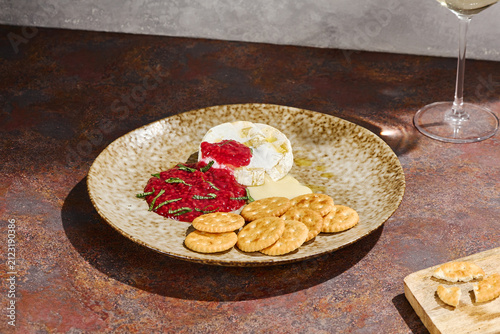 Foto Warm melting Camembert with tangy raspberry sauce and crisp crackers for an eleg