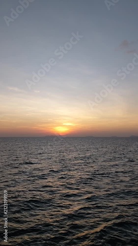 Beautiful golden sunset over the calm ocean horizon with gentle water waves and warm sky background.