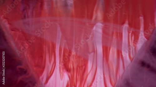 Paint wave. Geometric texture. Defocused pink red color ink in water acrylic liquid swirl moving on abstract dark black background.
