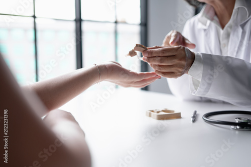 Doctor handing hearing aid to Asian female patient during hearing care consultation at medical clinic