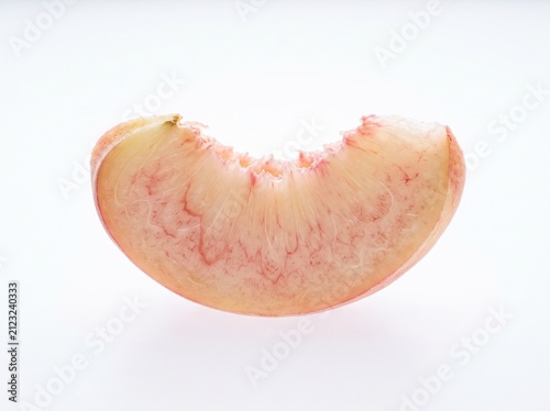 A juicy wedge of fresh peach showing detailed pulp structure and red fibrous veins