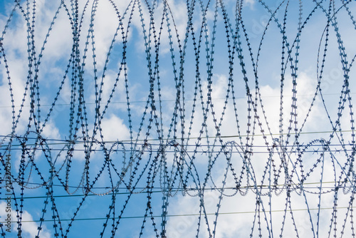 Obraz na płótnie a spiral barrier made of reinforced twisted barbed tape against a blue sky