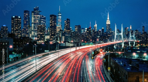 Dynamic city highway at night, long exposure captures vibrant light trails from moving vehicles, urban skyline.