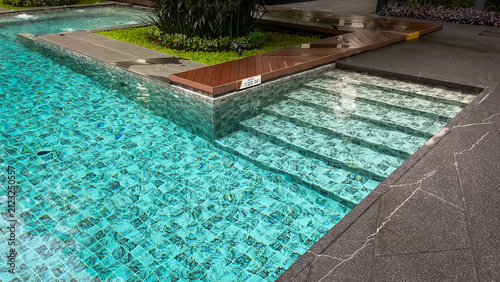 Cuadro en lienzo Tiled steps lead to a gently sloping entryway into the outdoor pool of a modern condominium in Thailand