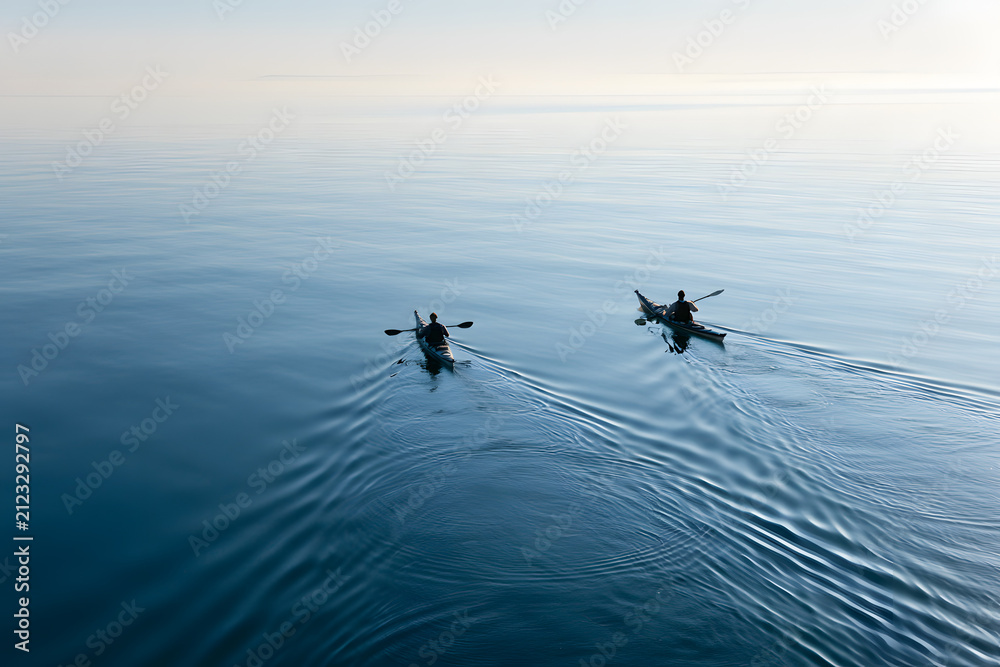 Fototapeta premium Kayakers Paddling Across Calm Waters of Puget Sound at Dawn with Smooth Reflections on Serene Surface