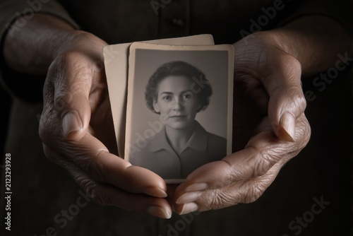 Hands holding an old black and white portrait photograph, family memory, remembrance, ancestry, emotional connection, heritage concept.