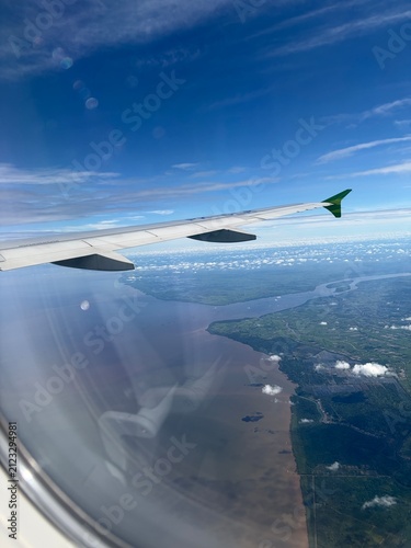 Scenic aerial view point of view from inside commercial airplane window during flight include with plane wing