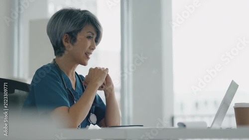 Doctor consults remotely via laptop in clinic office during advising call