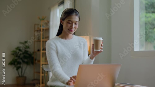 Woman works remotely from living room using laptop comfortably
