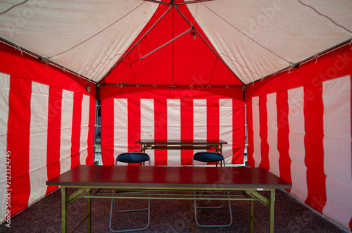 Symmetry view inside a traditional red and white striped event tent with tables and chairs in Japan