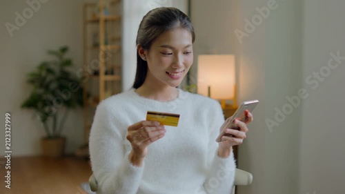 Asian female hold credit card and use mobile phone for online transactions