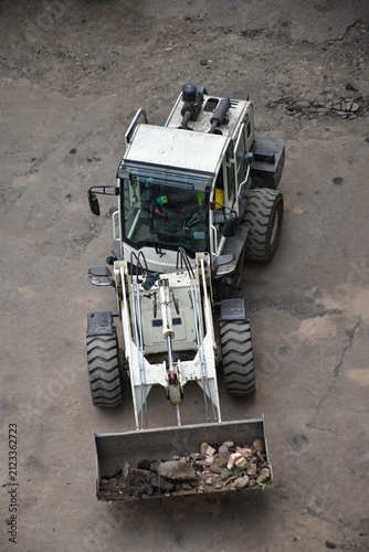 Aerial view of construction site where a front loader is loading soil, rocks, and debris into a dump truck, industrial work, excavation, and earthmoving processes