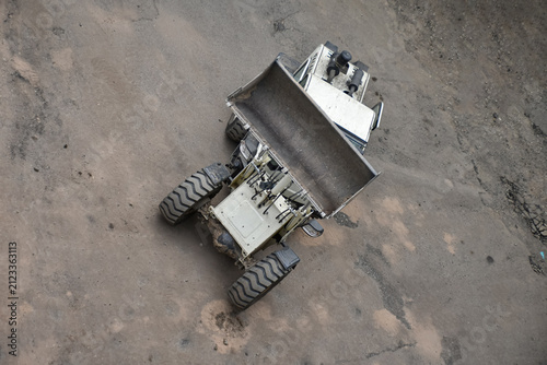 Aerial view of construction site where a front loader is loading soil, rocks, and debris into a dump truck, industrial work, excavation, and earthmoving processes