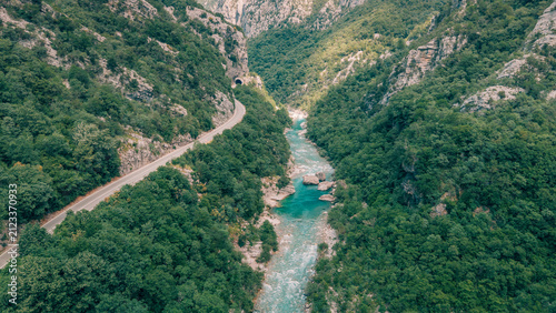 Canvas Print Aerial view discovering a scenic winding road through a lush green canyon with a
