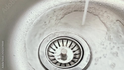 Water in the kitchen sink. Flowing from the tap water. Kitchen gadgets. Concept of saving water.