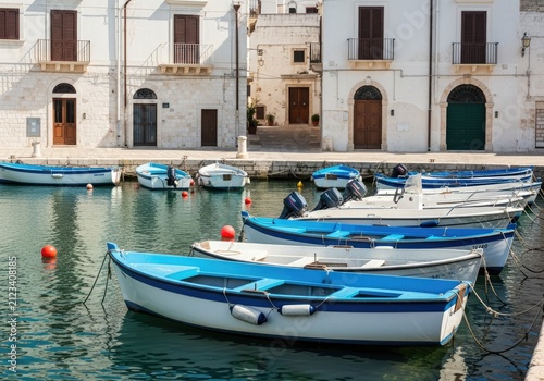 Boats docked in a picturesque Italian harbor with white buildings.