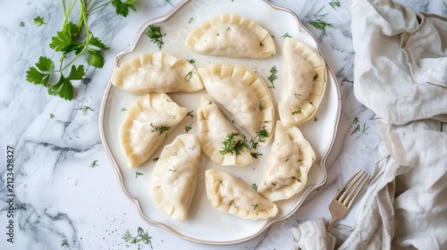 Handmade Polish pierogi filled with savory potato and cottage cheese, garnished with caramelized onions and fresh dill, on a dark slate background, top view.
