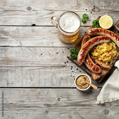 Grilled german sausages with sauerkraut mustard and beer on rustic wood table