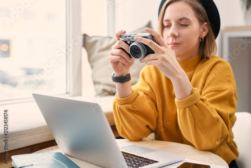 Female photographer with camera, laptop and smart phone at cafe