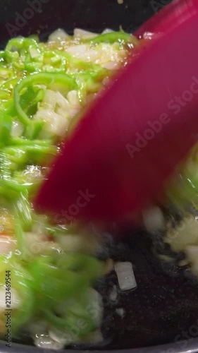 Close-up of fresh colorful vegetables being sauteed in a hot pan, featuring diced potatoes, carrots, green peppers, and red chili peppers being stirred with a spatula. Perfect for cooking tutorials, h