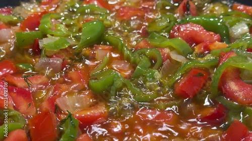 Close-up of fresh colorful vegetables being sauteed in a hot pan, featuring diced potatoes, carrots, green peppers, and red chili peppers being stirred with a spatula. Perfect for cooking tutorials, h