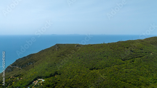 Bild auf Leinwand Aerial view of the green, densely vegetated slope of Mount Circeo descending toward the blue sea, in Italy