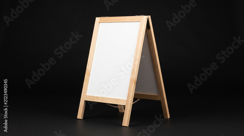 Blank white wooden sandwich board easel on black background.