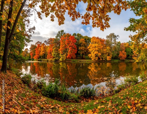 A serene autumnal landscape with vibrant trees reflected in a calm lake