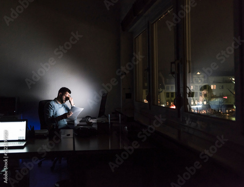 Exhausted businessman sitting at desk in his office by night