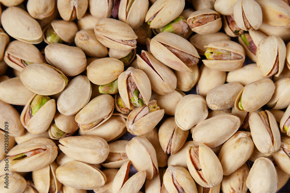 Fototapeta premium background of Pistachios filling the frame, showing cracked shells and vibrant green nuts, offering a delicious and healthy snack