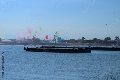 A river barge passes near Giurgiu port as colored smoke rises during Danube Parade
