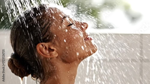 Close-up of a woman enjoying a refreshing outdoor shower with flowing water, promoting wellness, skincare, hygiene, self care, relaxation, and healthy lifestyle in natural light.