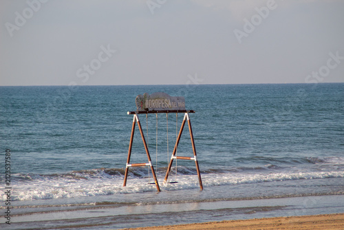 Fotografie Wooden swing in the Mediterranean Sea at La Concha Beach, Oropesa del Mar, Spain