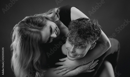 Foto Young couple hugging and laughing on a dark studio background, portraying joy an