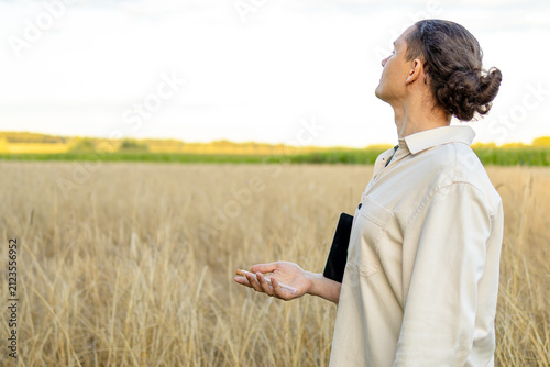 Agronomist gazes across wheat field during sunrise inspection. Concept of vigilance and stewardship in sustainable farming practice.