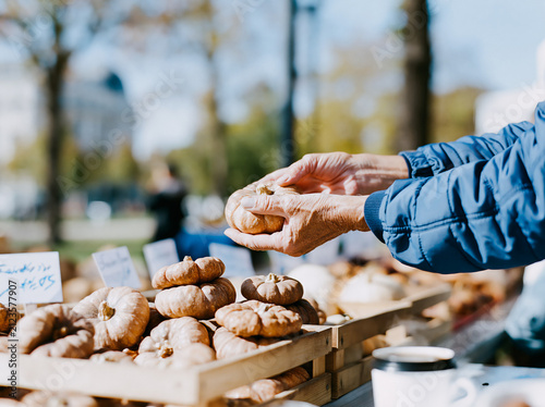 Hand Picking Up Fresh Pastry at Outdoor Bakery Market Stall in Daylight