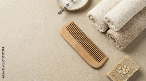 Natural wooden comb, rolled towels, handmade soap, and lavender sprigs for organic spa and self-care routines.